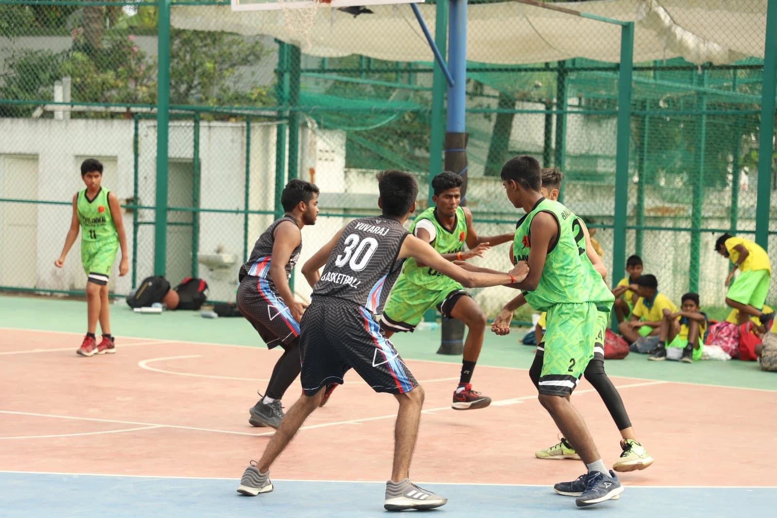 Students playing competitive basketball on outdoor court