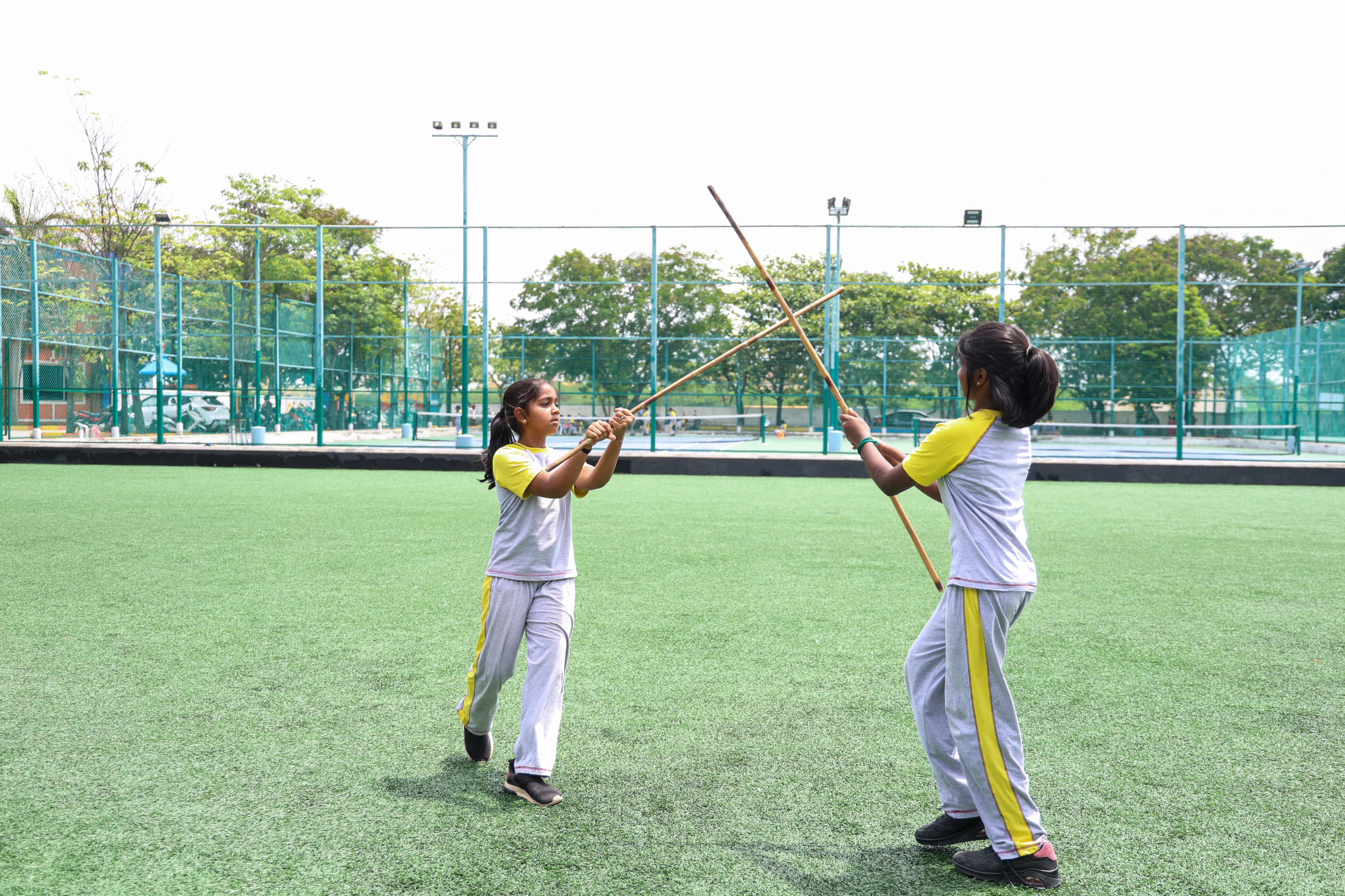 Students practising traditional Silambam stick sparring on the outdoor sports field
